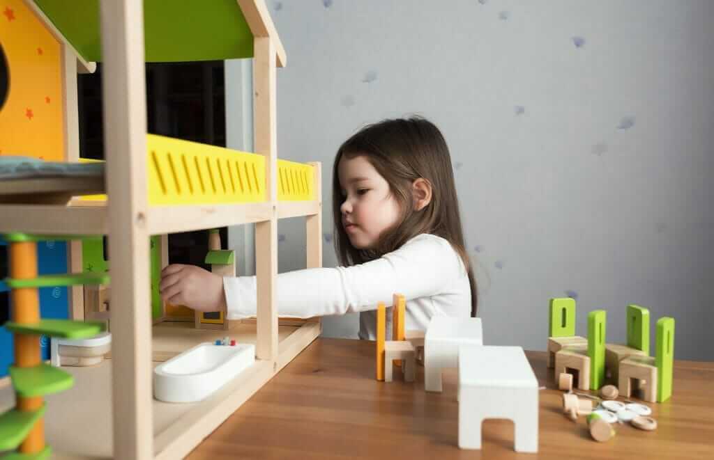 Young girl playing with her dollhouse